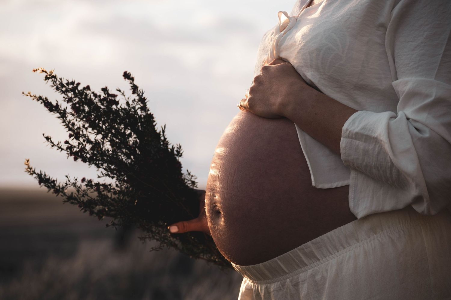 Backlit maternity photography capturing tender moments at sunset.
