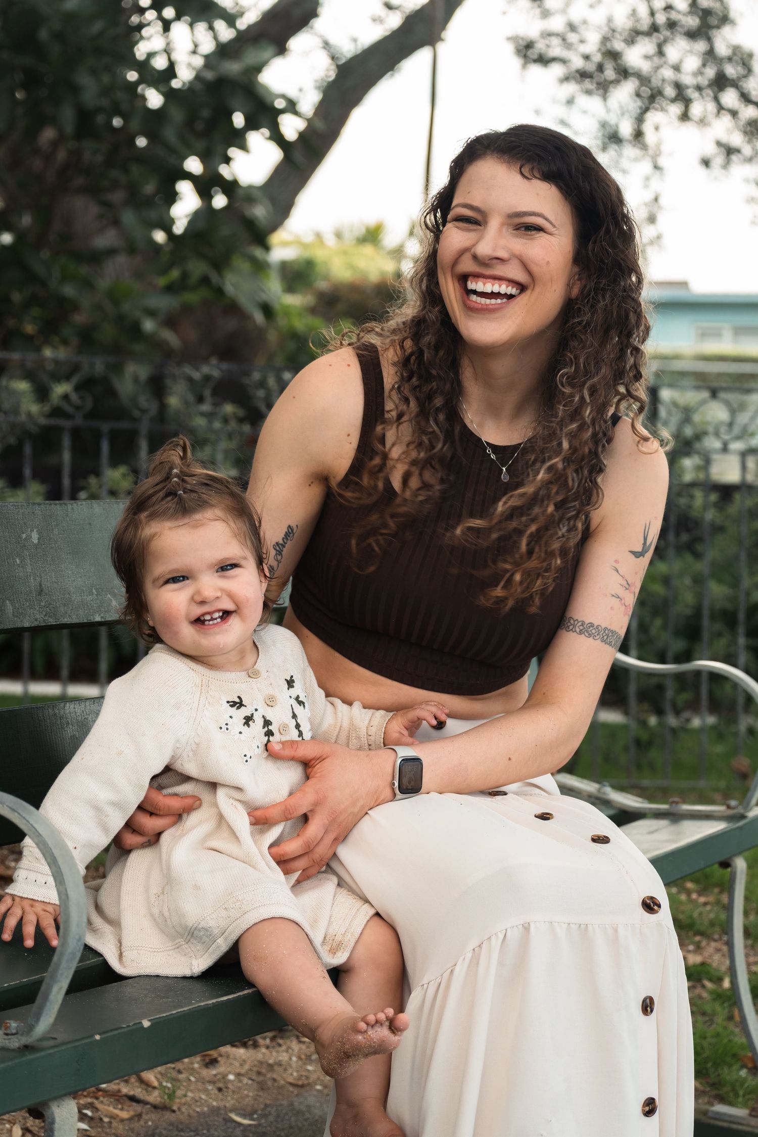 A joyful moment shared between a parent and young child sitting together on a garden bench in an outdoor setting.