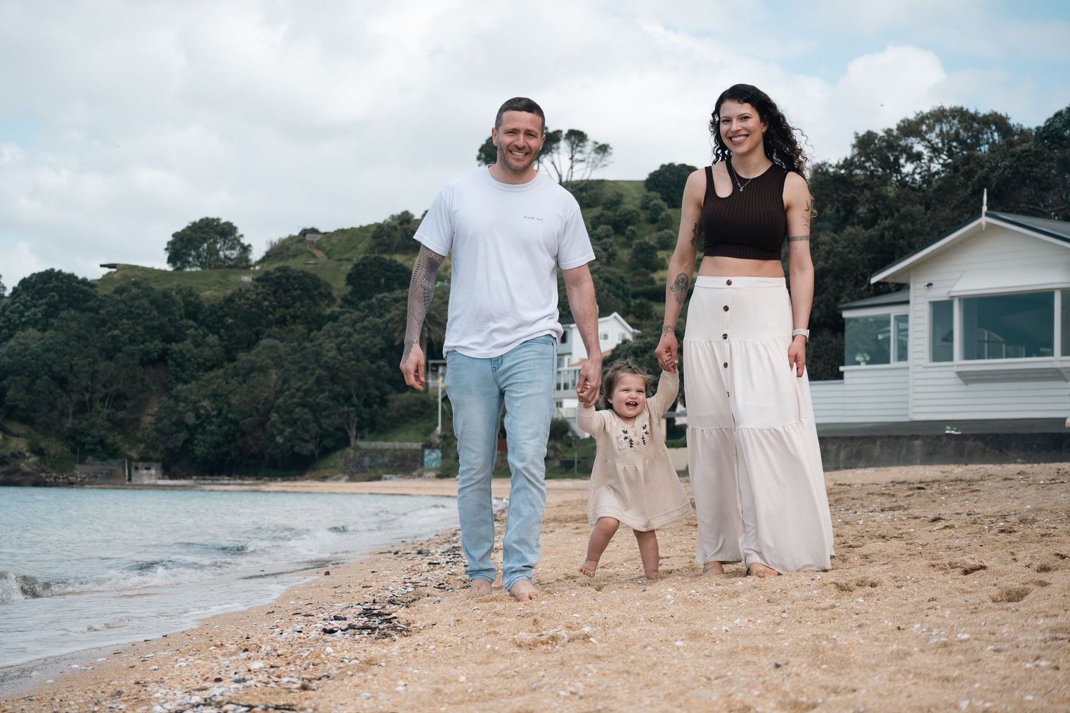 Family walking together along a scenic beach shoreline during a cloudy day.