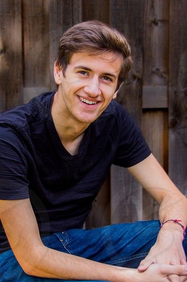 A series of casual portrait photos showing someone in a navy t-shirt against a wooden fence background.