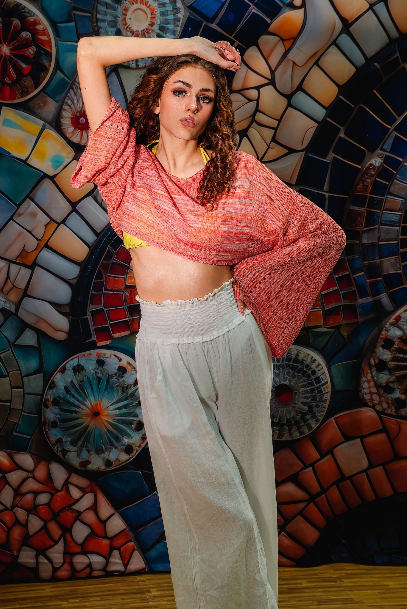 Dance poses against colorful mosaic wall background in coral top and flowy skirt.