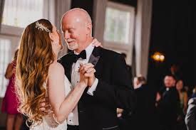 A romantic dance moment captured at an elegant wedding reception in a dimly lit ballroom.