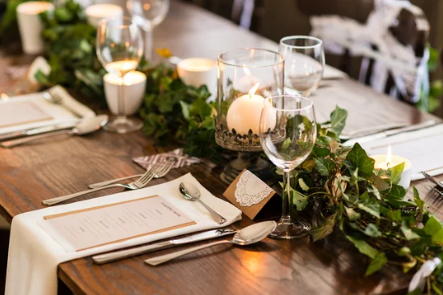 Elegant wedding table setting with greenery garland and candlelight.