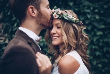 A romantic wedding couple shares intimate moments in a garden setting with ivy covered walls.