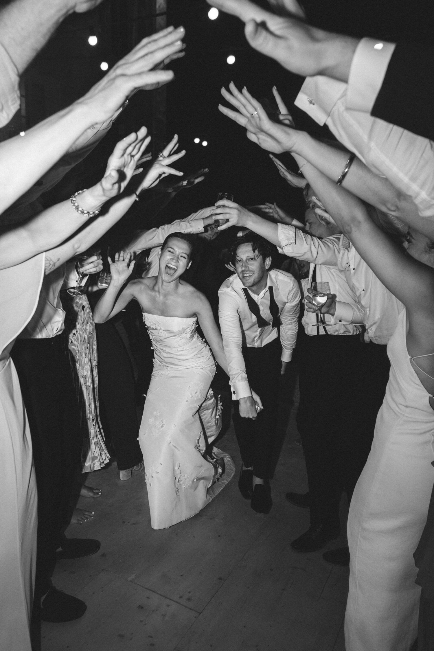 Wedding party dancing and celebrating with raised hands at a reception.