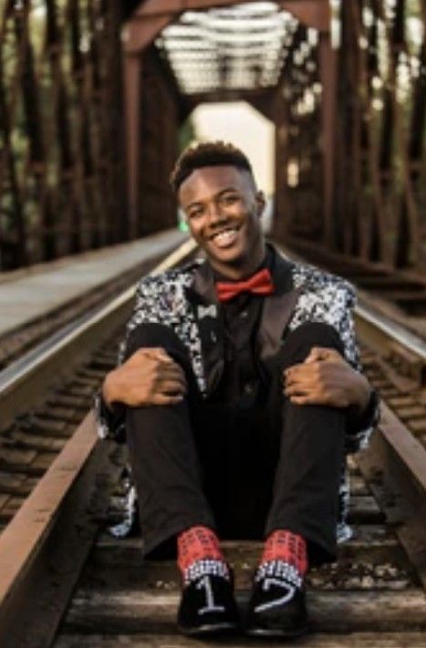 A joyful portrait session on railroad tracks featuring formal attire and a bowtie in a wooded setting.