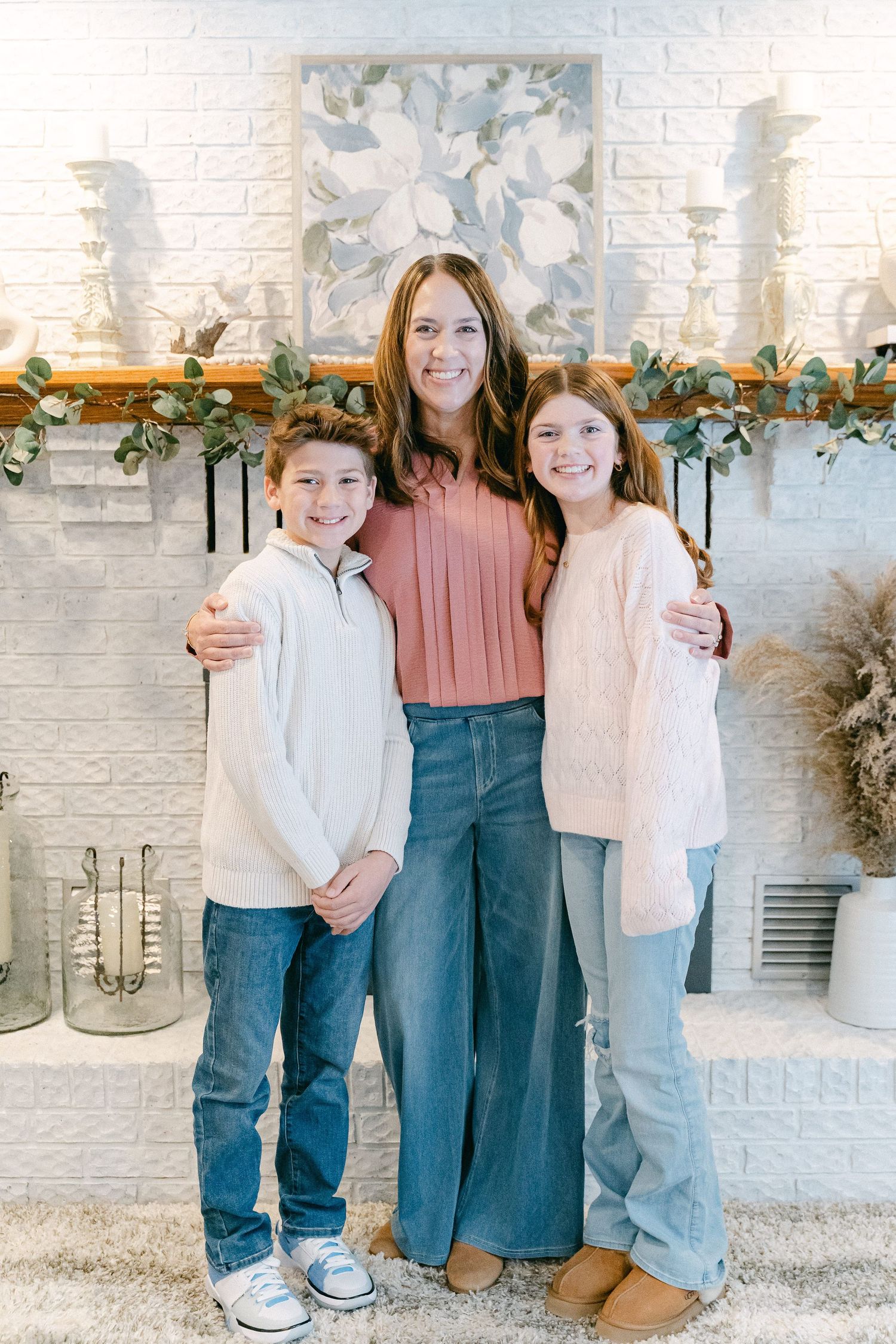 Family members posing casually in front of a modern white brick fireplace with holiday greenery.