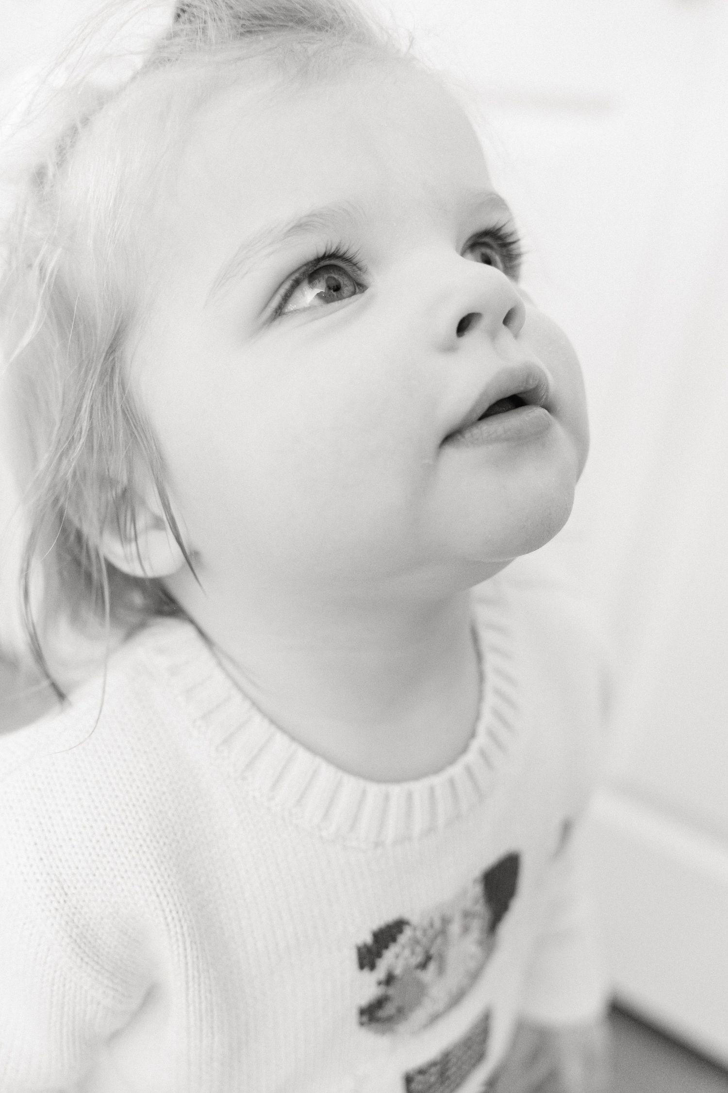 Close-up portraits of a child looking upward with an innocent expression in black and white.