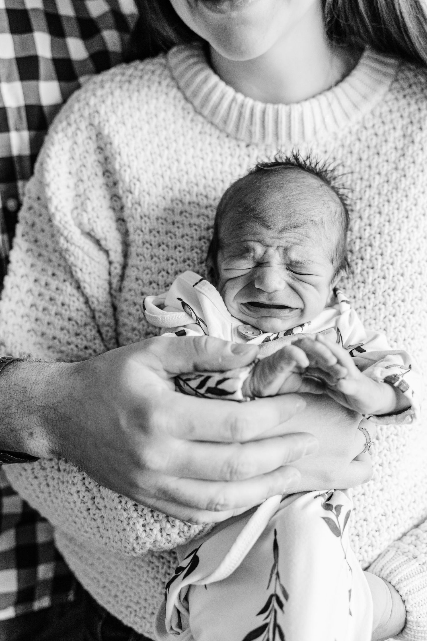 A series of black and white photos showing a sleeping newborn baby cradled in a blanket.