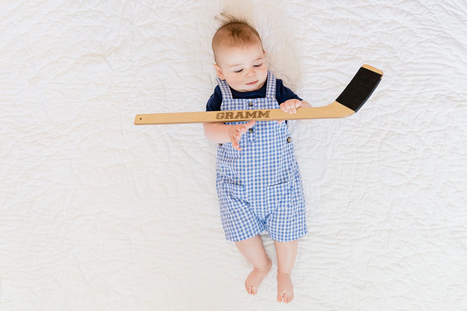 A series of four connected photos showing a small child in blue gingham clothing lying on a white surface.