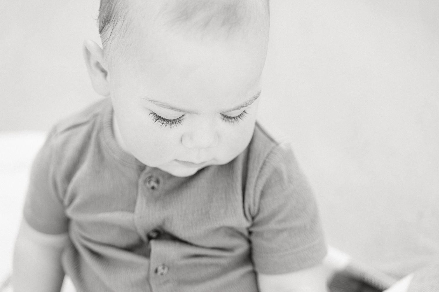 A black and white photo series shows a baby's progression from sitting to crawling across a hardwood floor.