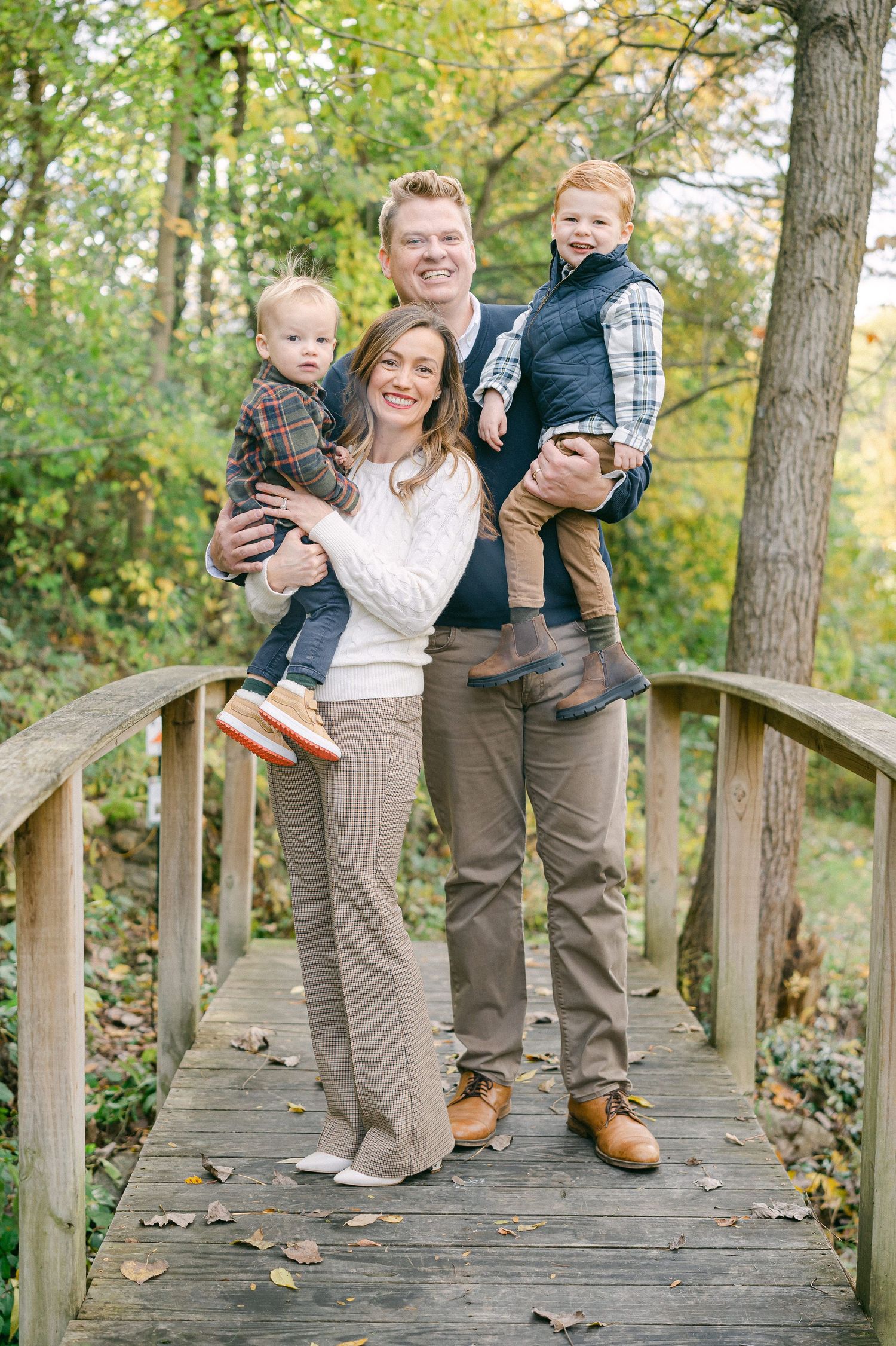 Family photos taken on a wooden walkway with fall foliage in the background.