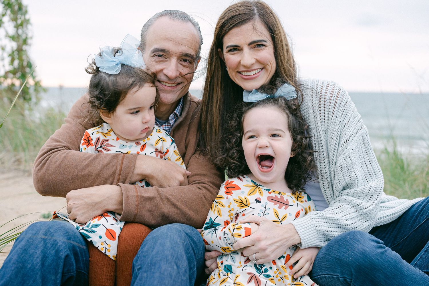 A family shares joyful moments together outdoors during a photo session in casual attire.