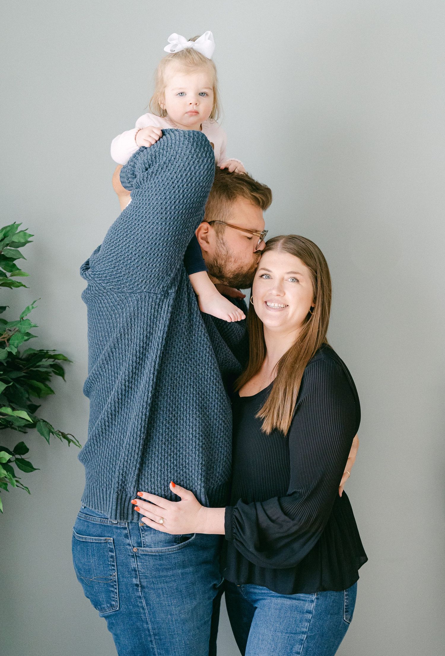 Playful couple in matching black and blue outfits embracing and laughing against a grey backdrop.