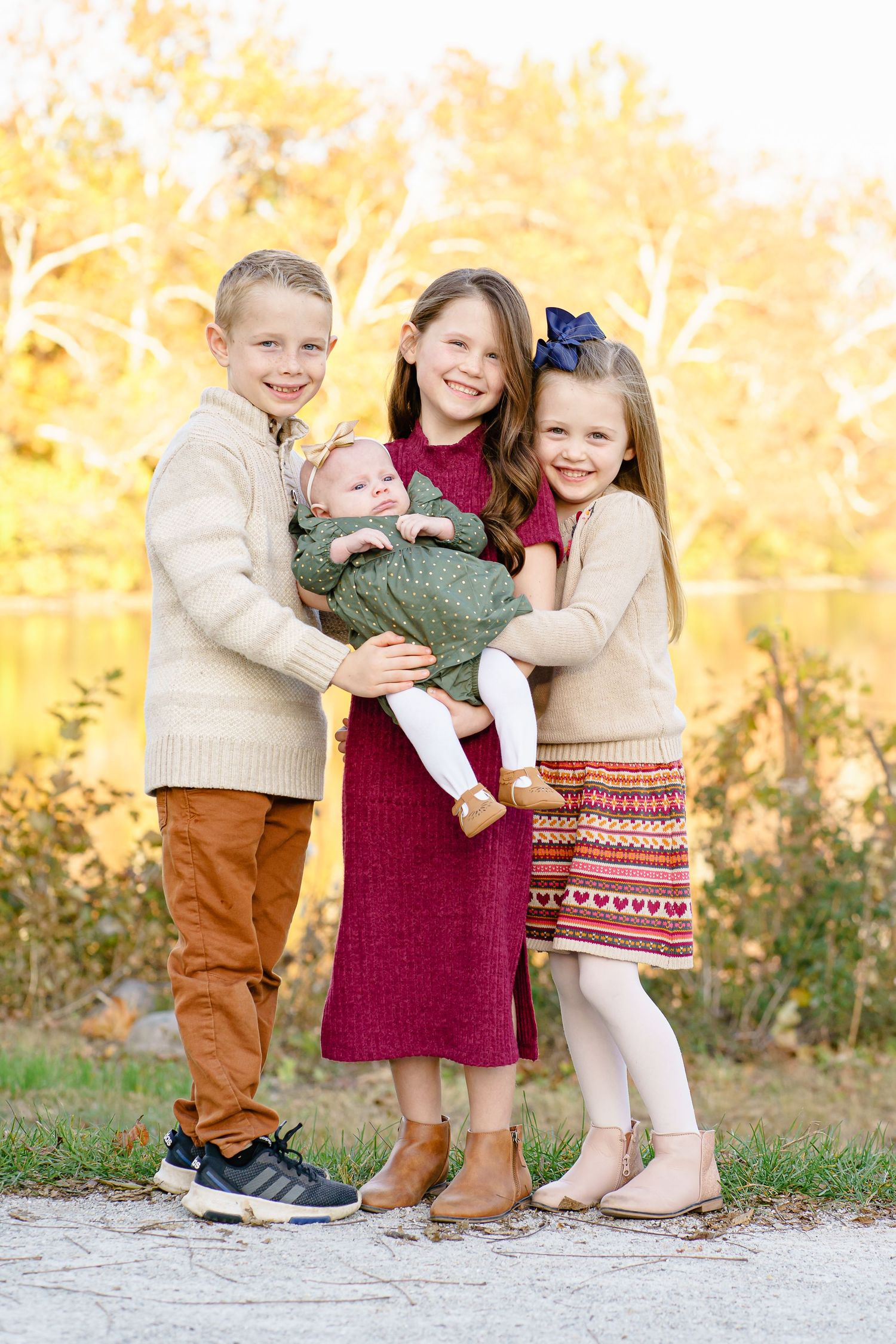 Children in coordinated fall outfits stand together against a golden autumn background with warm lighting.