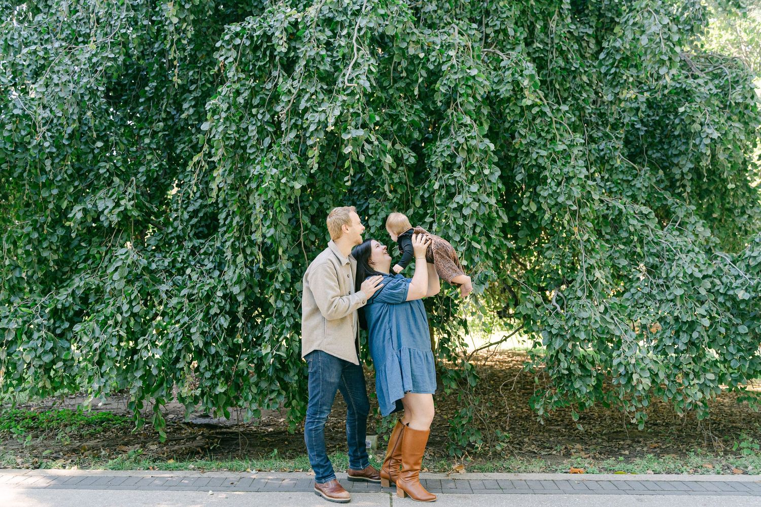 A couple embraces in a romantic outdoor photoshoot surrounded by lush green foliage.