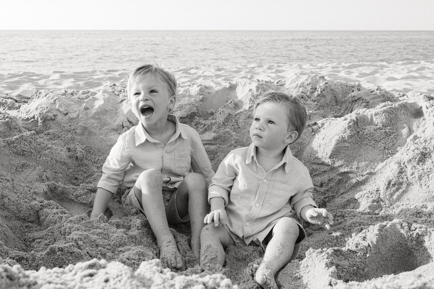 Children playing and laughing together in a sandy beach area while having fun outdoors.