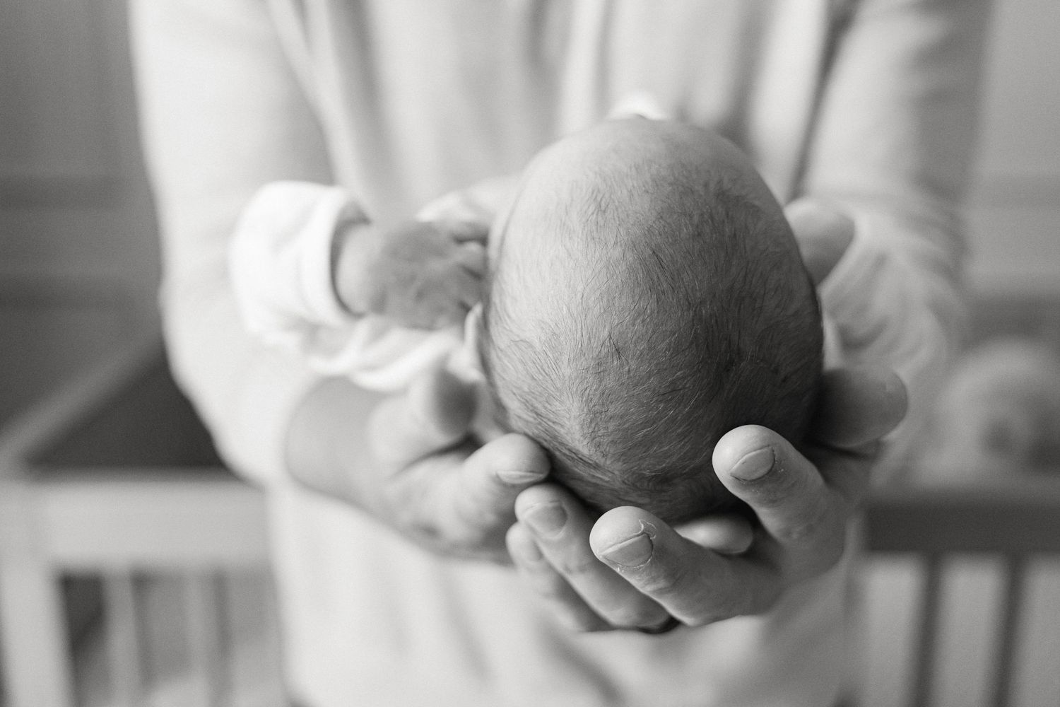 A series of close-up shots showing hands gently cradling a newborn baby.