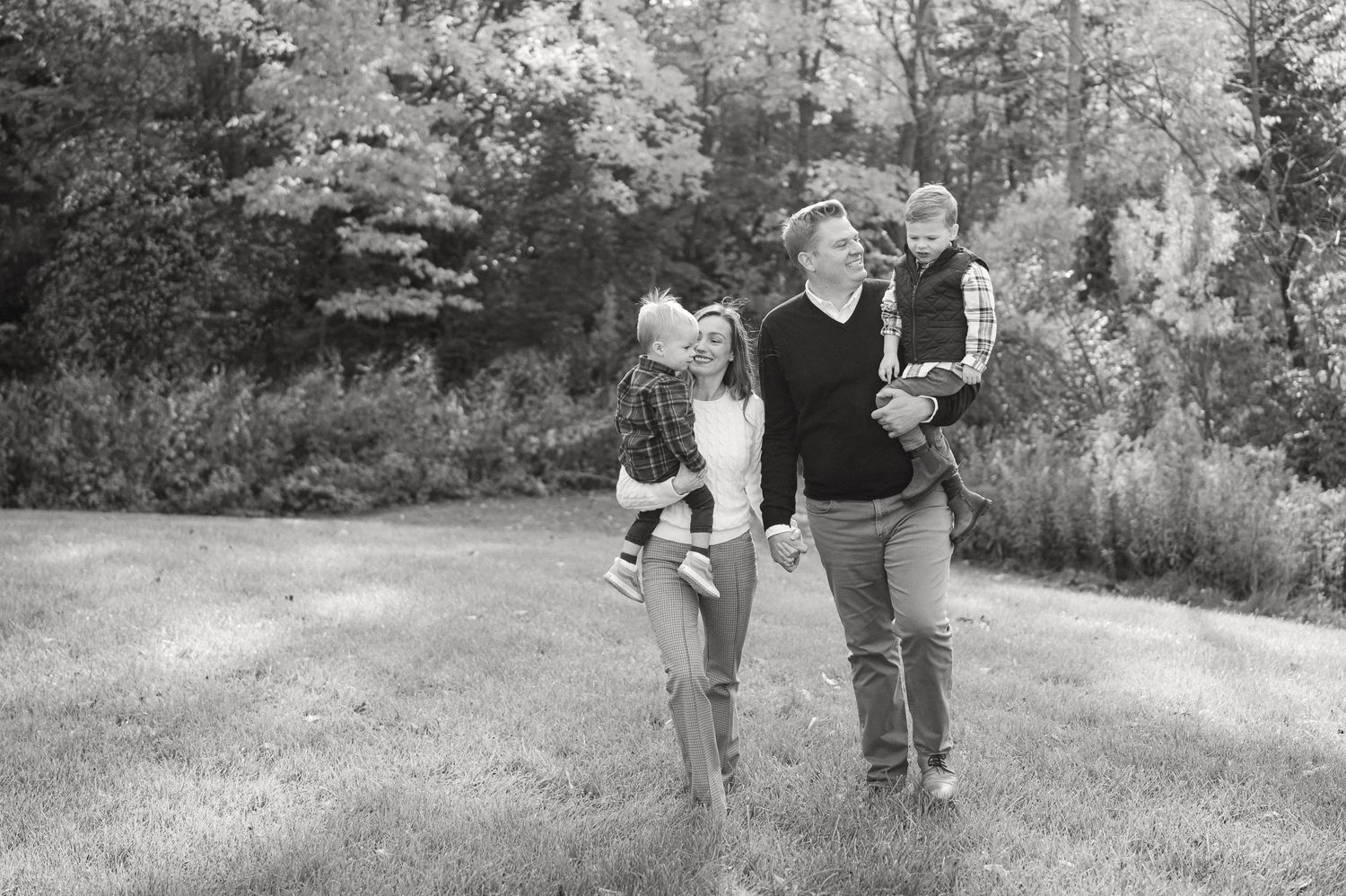Family photoshoot in a park setting with people walking and embracing on a sunny autumn day.