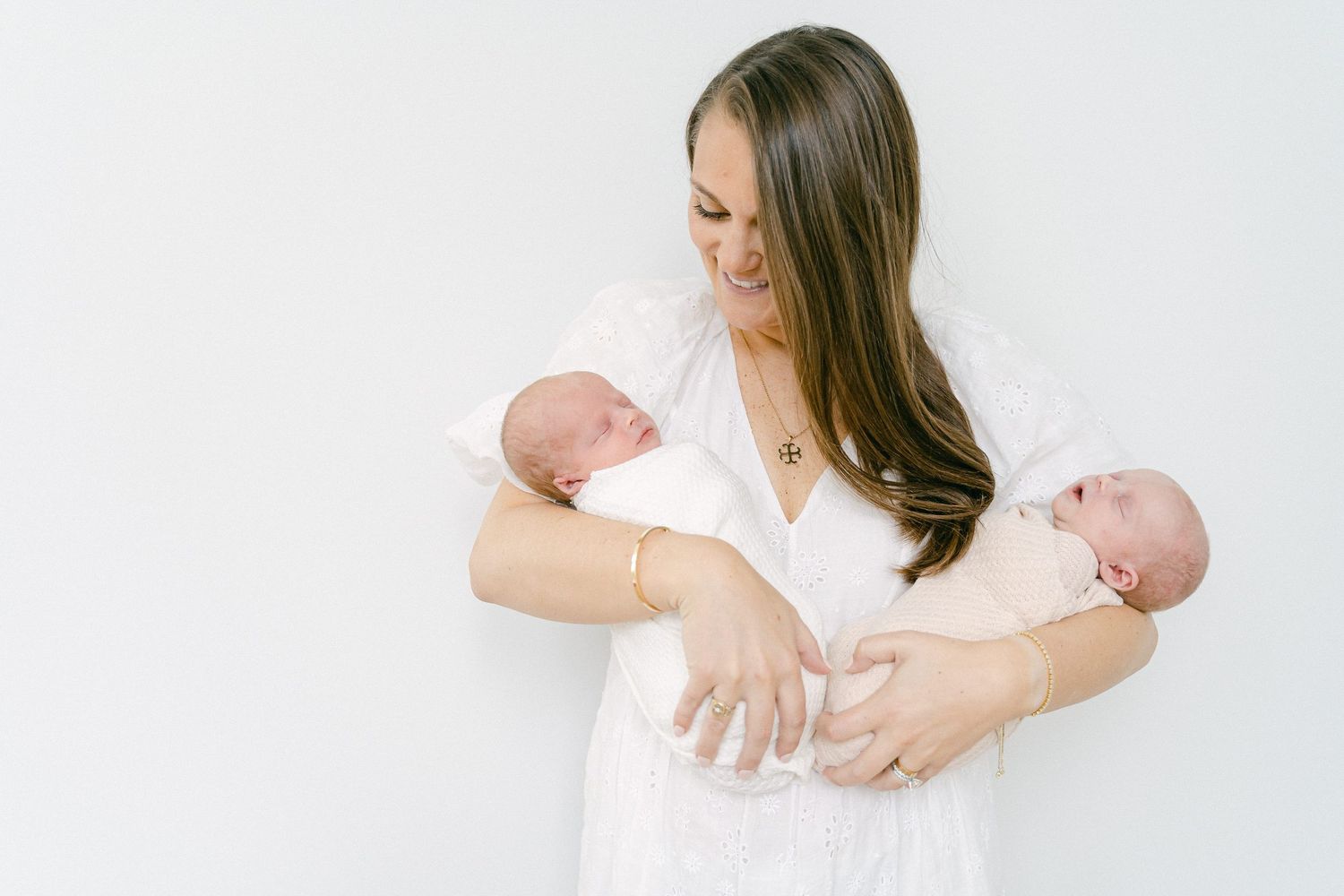 A series of four tender moments between a parent and newborn baby in white studio portraits.