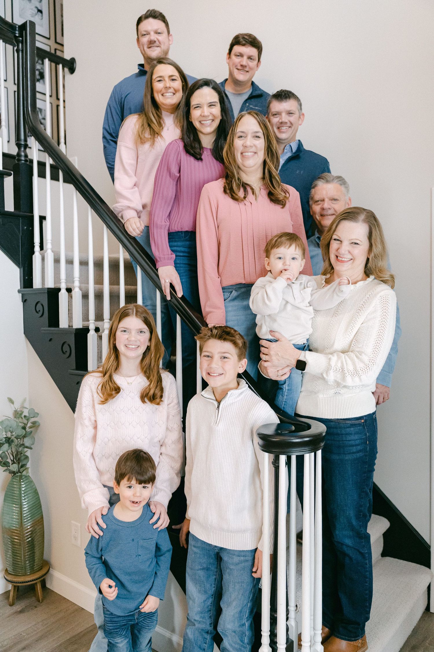 Family portrait session showing multiple generations in coordinated pink and white outfits posing on a staircase.