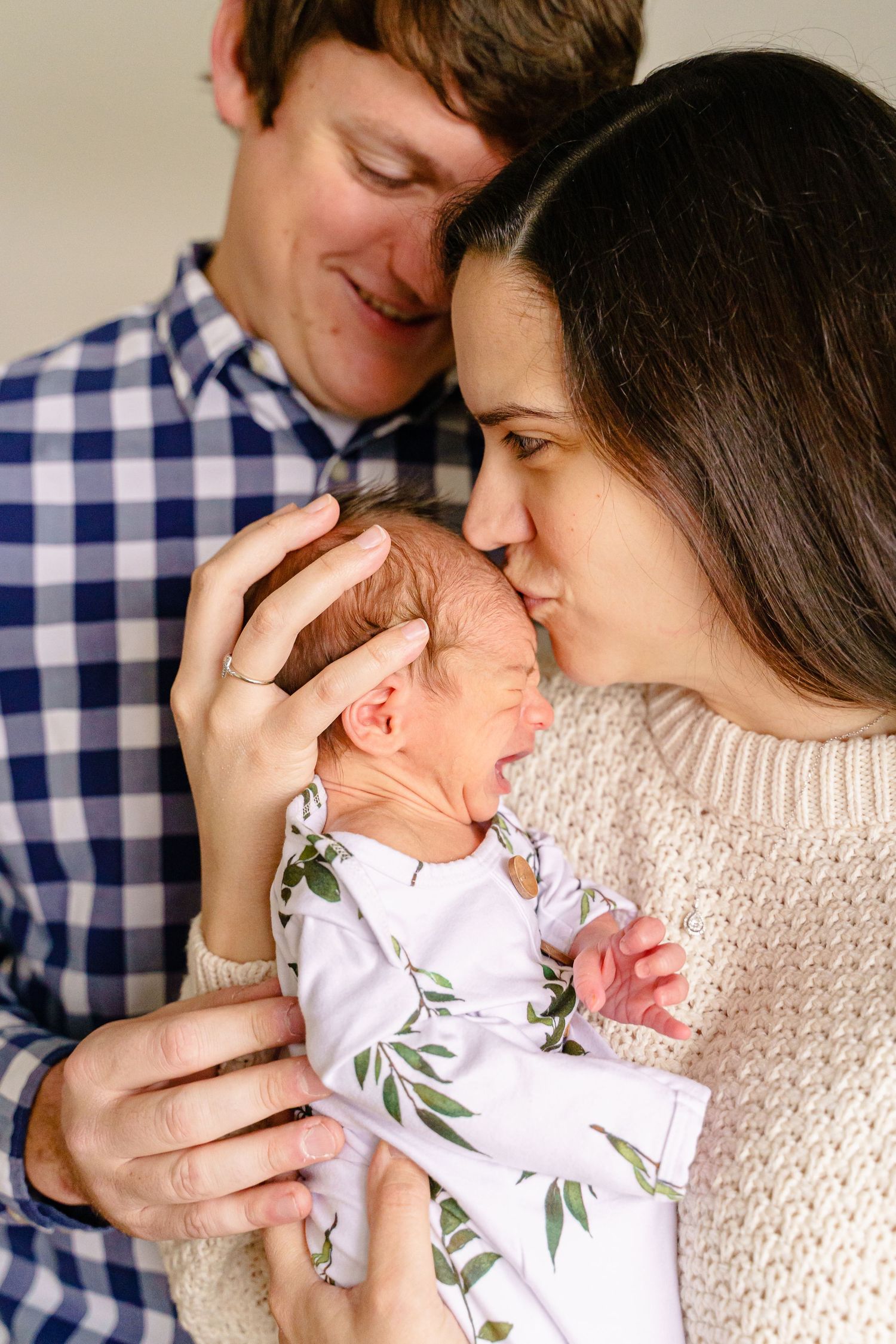 New parents share an intimate moment with their newborn baby wearing a floral onesie.