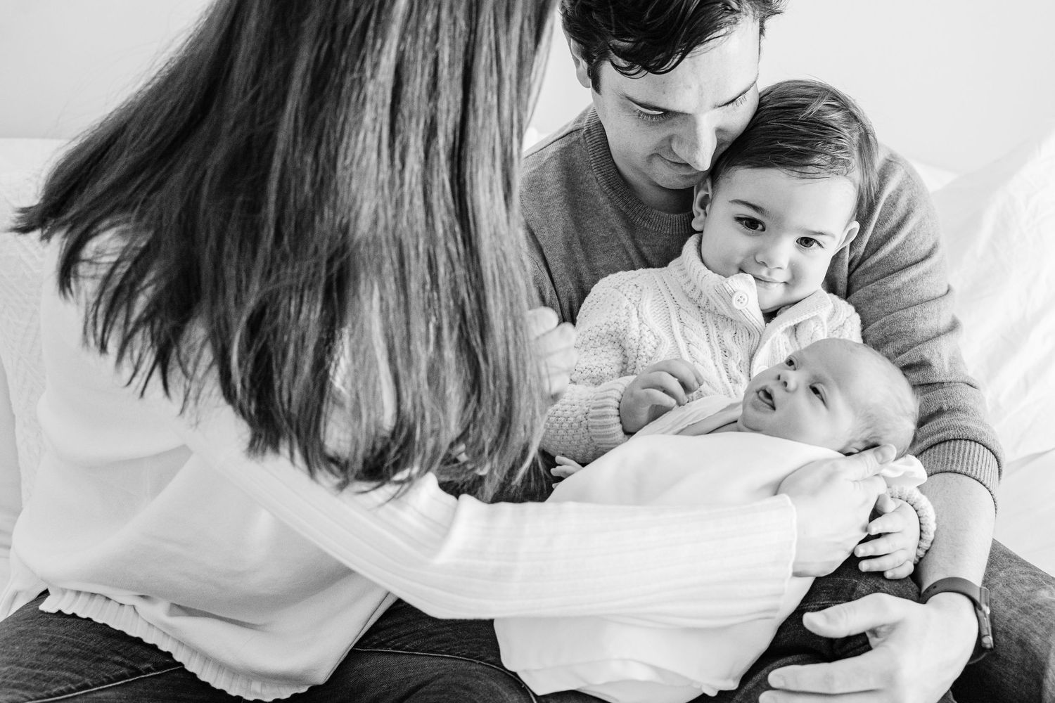 Black and white intimate family moment showing parents cradling and interacting with their baby.
