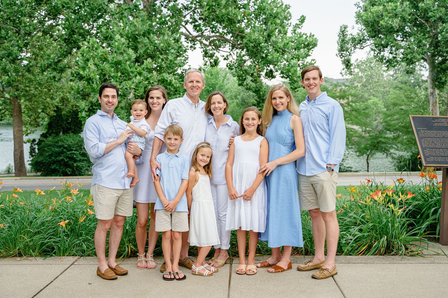 Family group photo session in a park with everyone wearing coordinated blue and white summer attire.