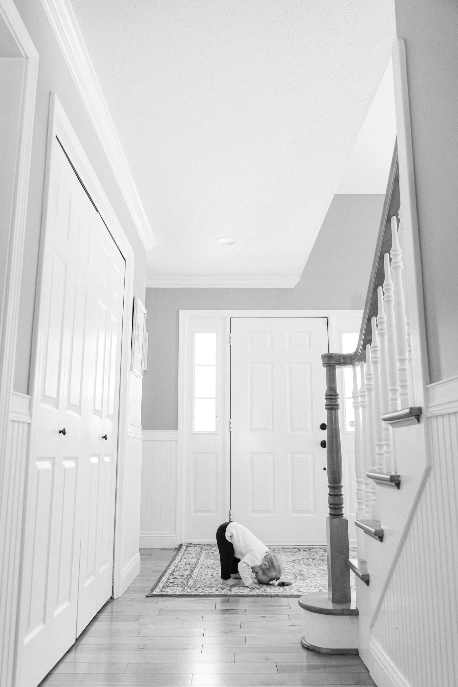 Long white hallway with hardwood flooring and natural light streaming in from windows.