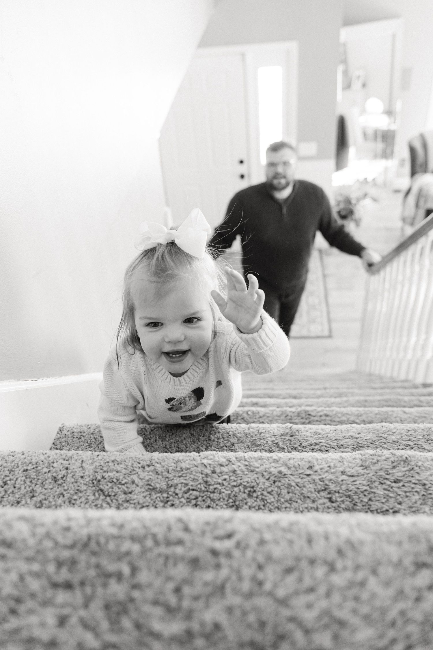 A sequence of black and white photos showing a baby crawling up carpeted stairs with joyful expressions.