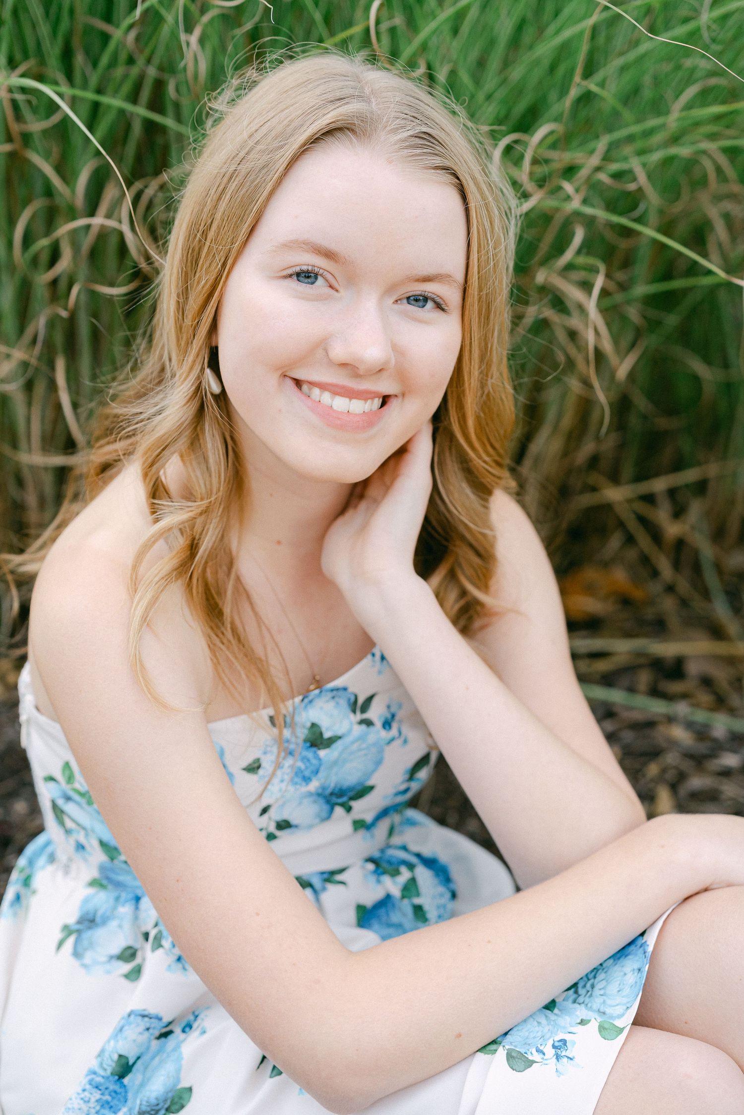 A series of four similar photos showing someone in a blue floral dress sitting outdoors against a green foliage background.