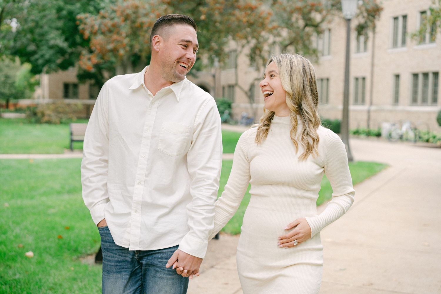 A couple in white outfits shares a romantic moment while walking together on a garden pathway.