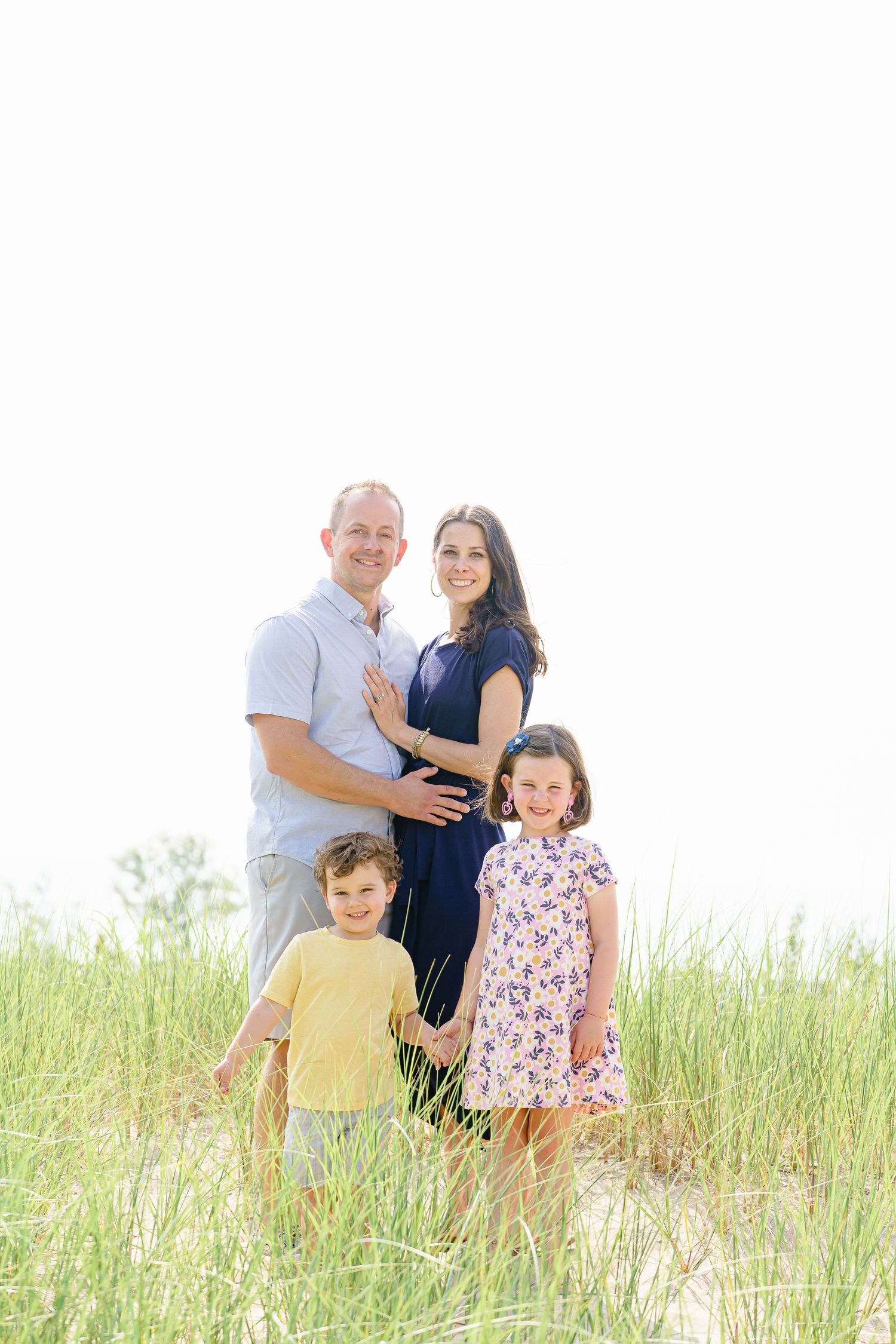 Family enjoying a playful moment together in tall grass during a golden hour outdoor photoshoot.