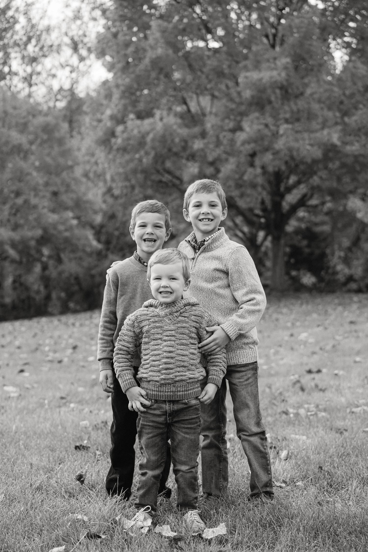 Black and white photo of children playing and laughing together outdoors on a grassy hill.
