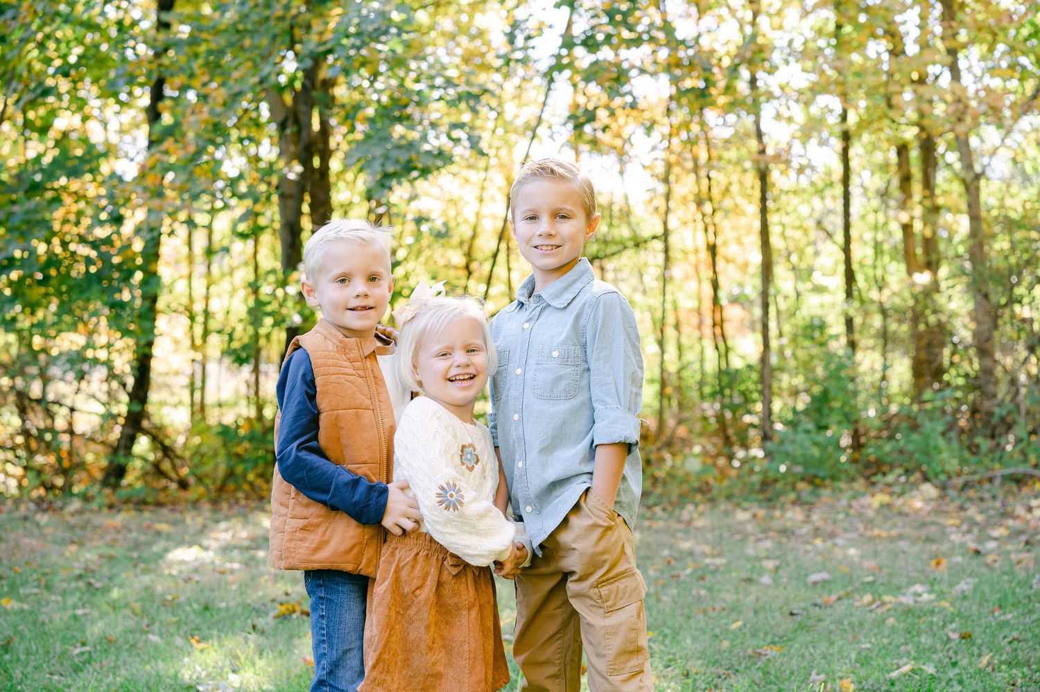 Family enjoying a tender moment together in a sunlit autumn forest setting.