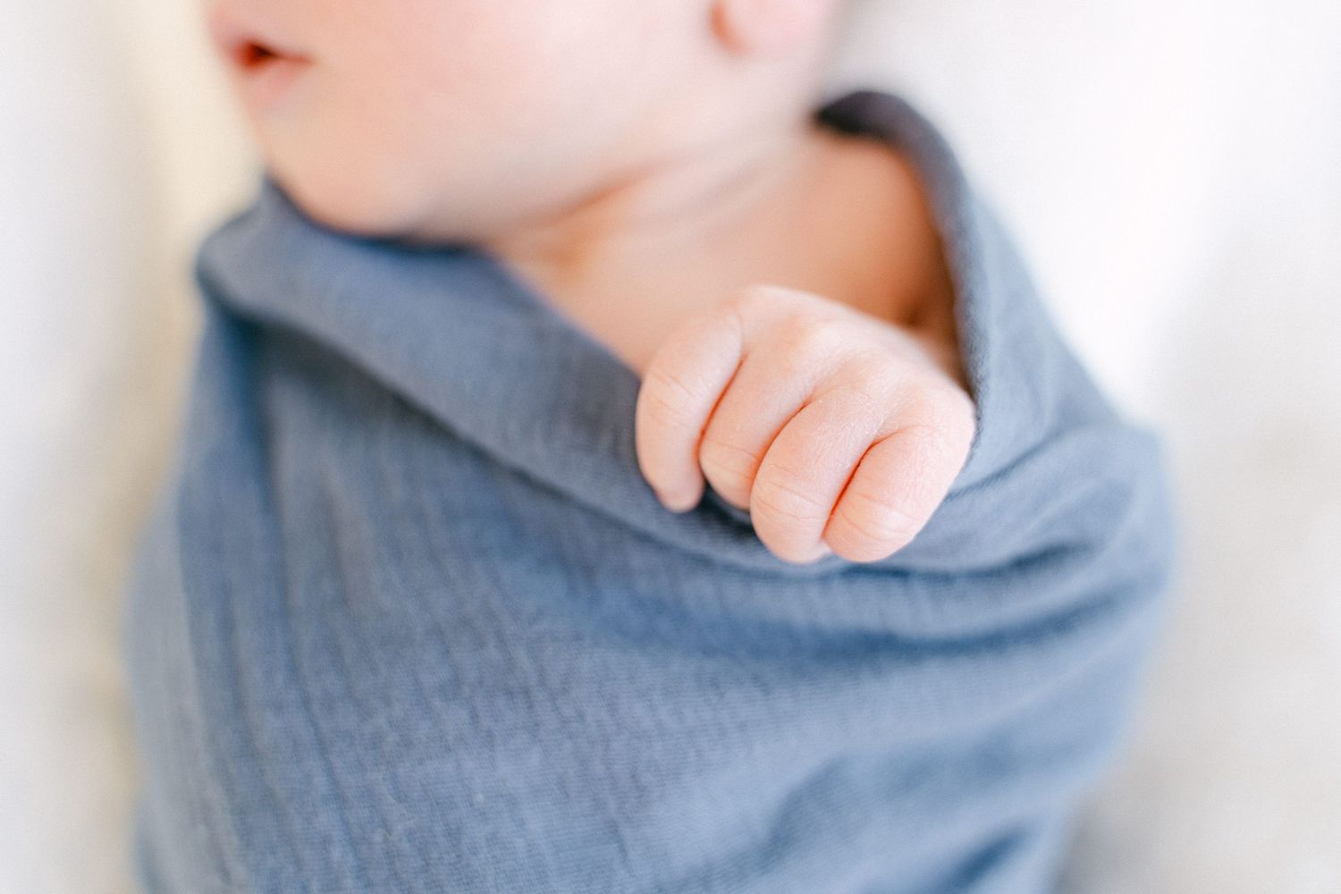 A close-up view of small hands reaching up against a soft blue background.