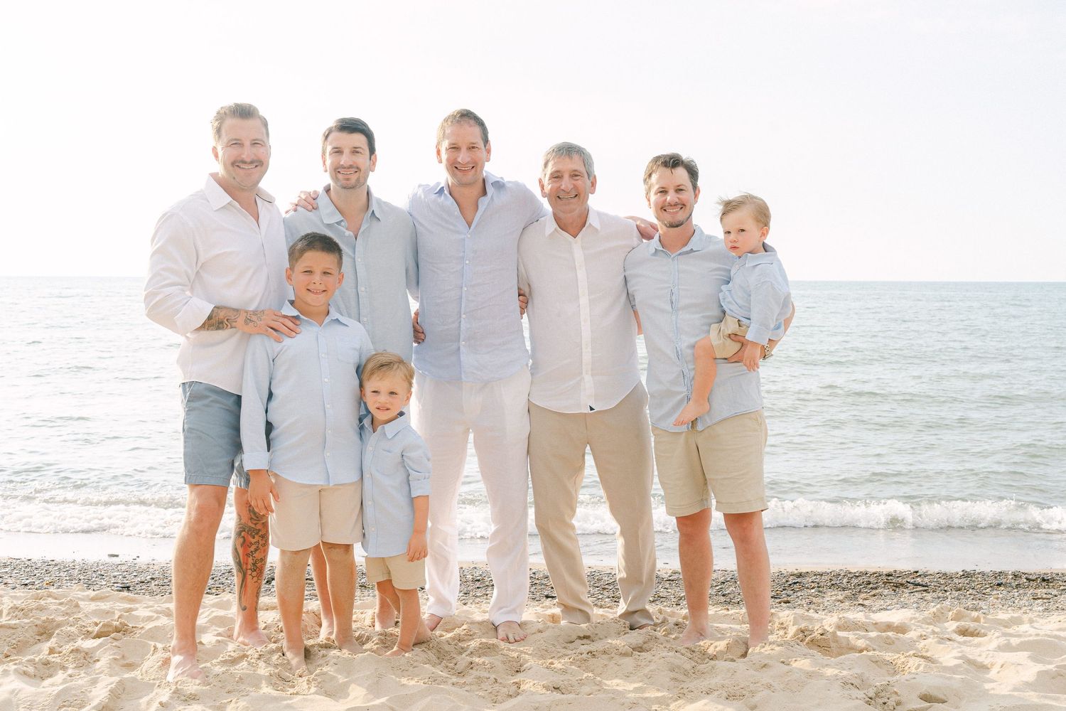 Casual beach family photo with ocean waves visible in background.
