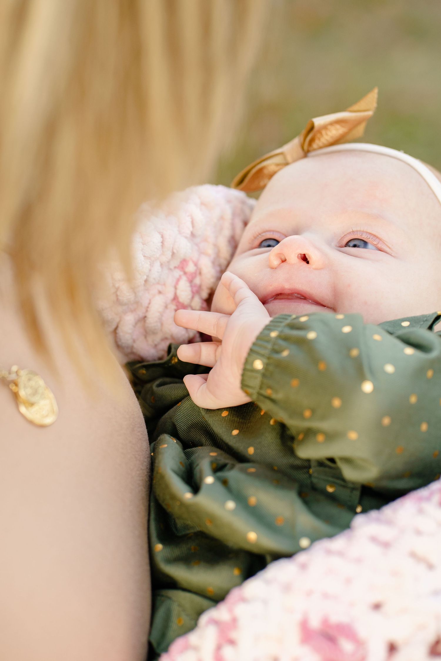 A baby's hand grasps a polka dot blanket or fabric in a close-up shot.