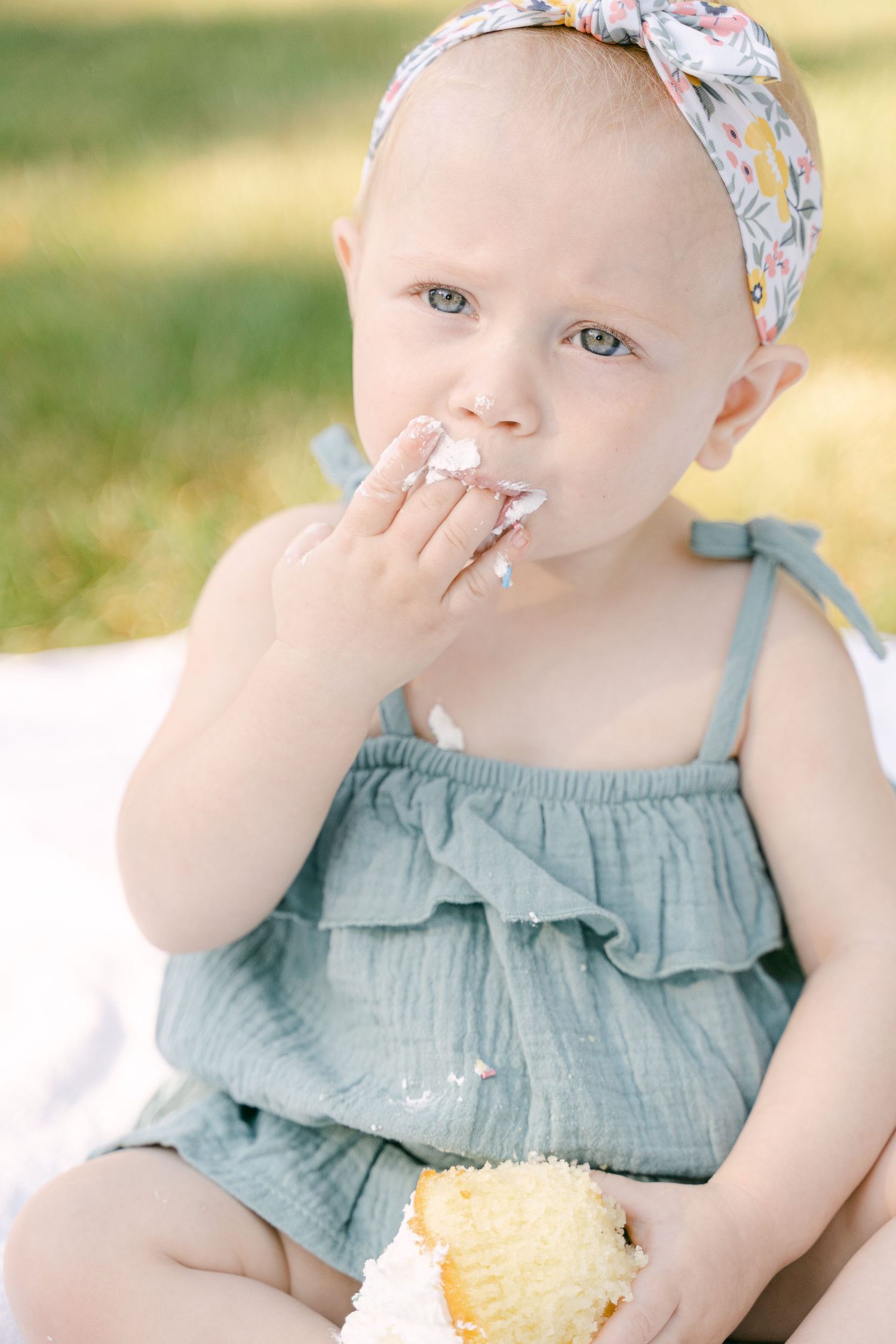 A series of photos showing a little one in blue clothing eating a piece of cake on a sunny day.