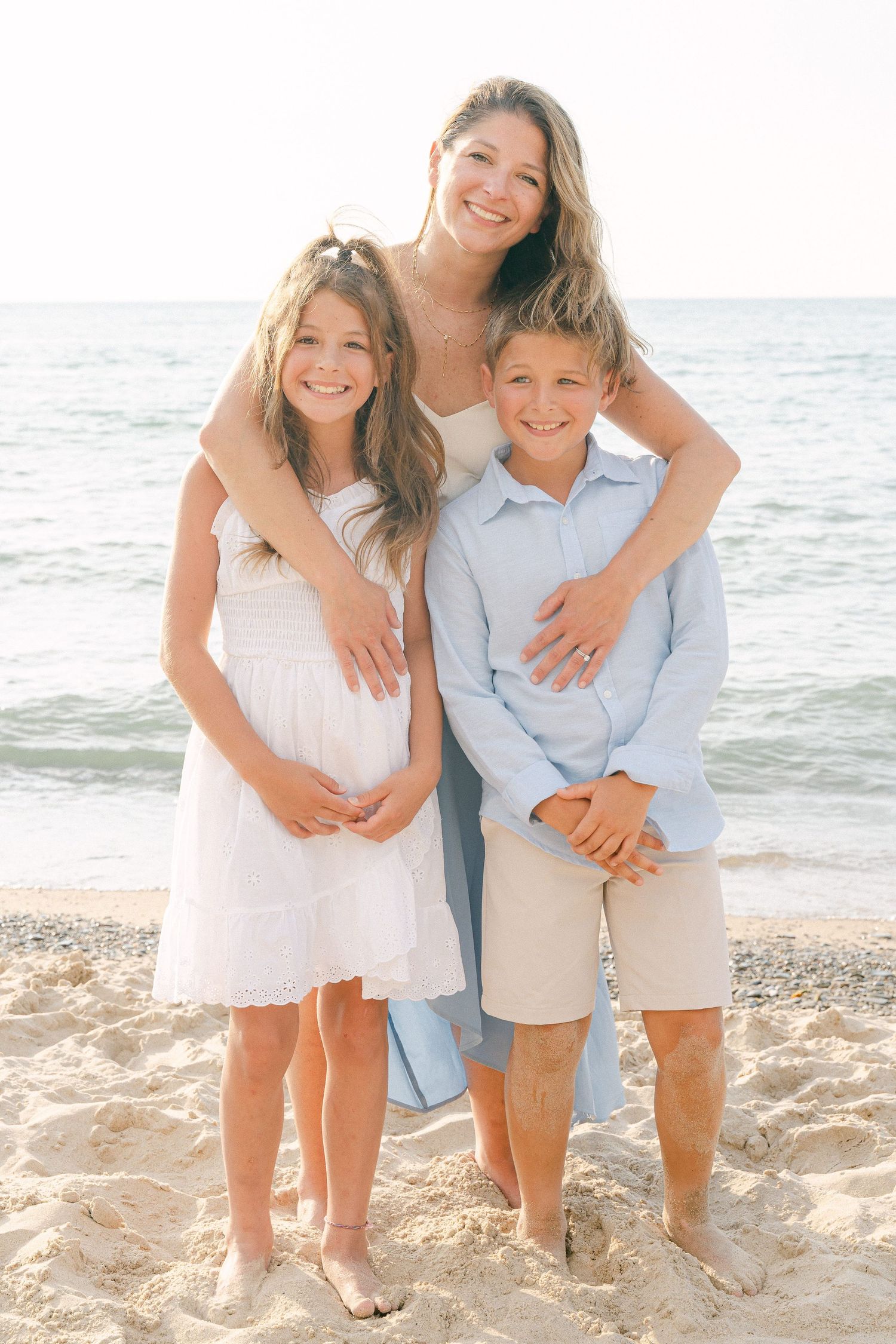 A sunny beach portrait of a family group posing together by the ocean.