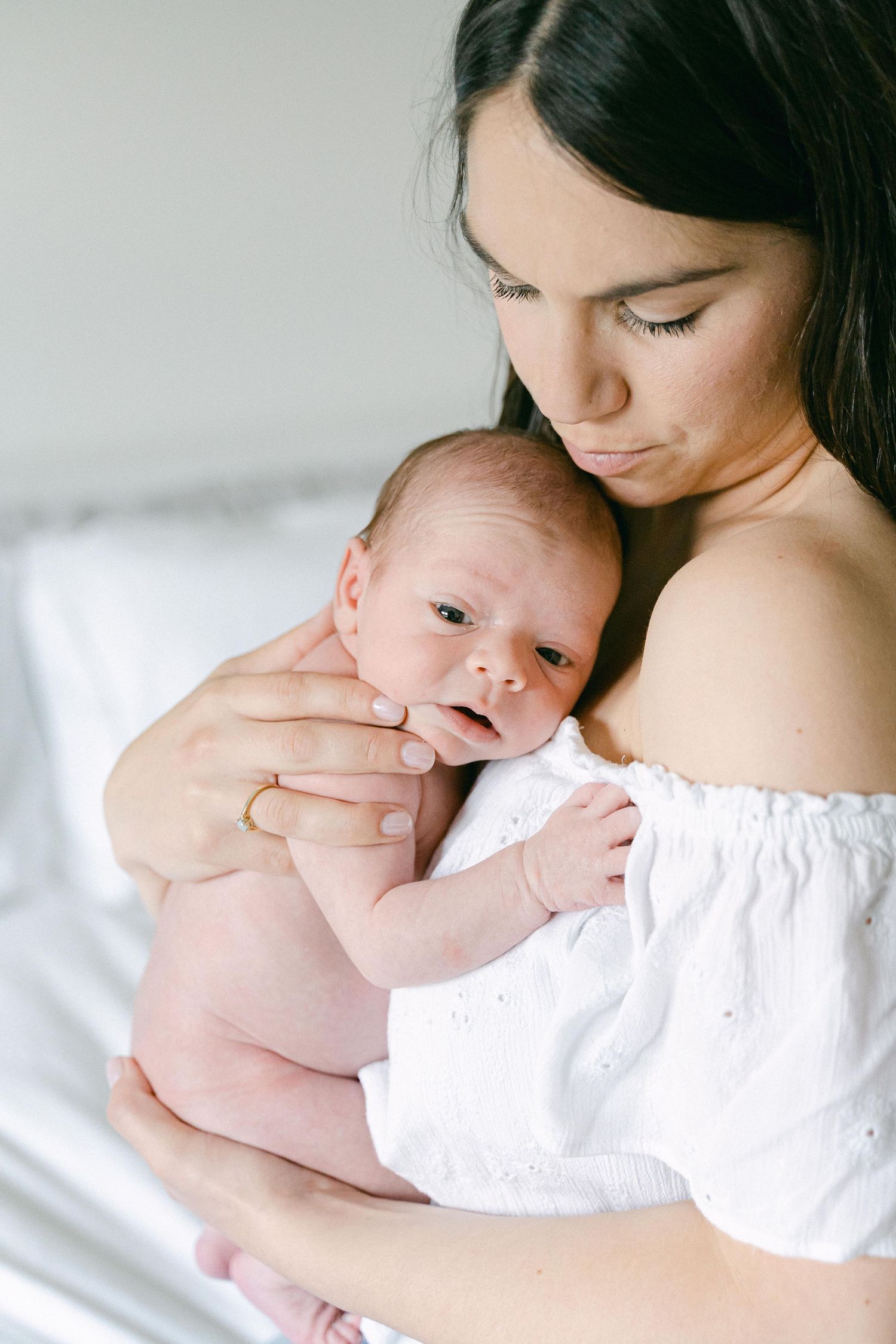 Intimate monochrome portraits capturing gentle maternal moments in white clothing.