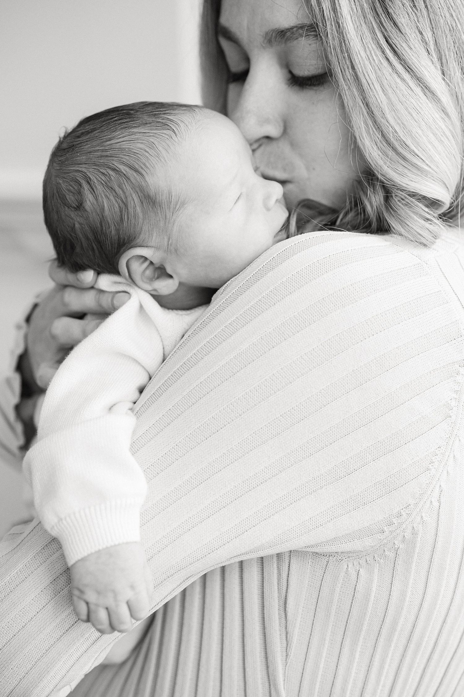 A tender moment between parent and newborn in black and white.