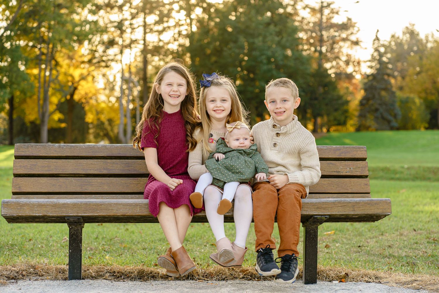 A group sits together on a wooden park bench during golden hour in an autumn setting.
