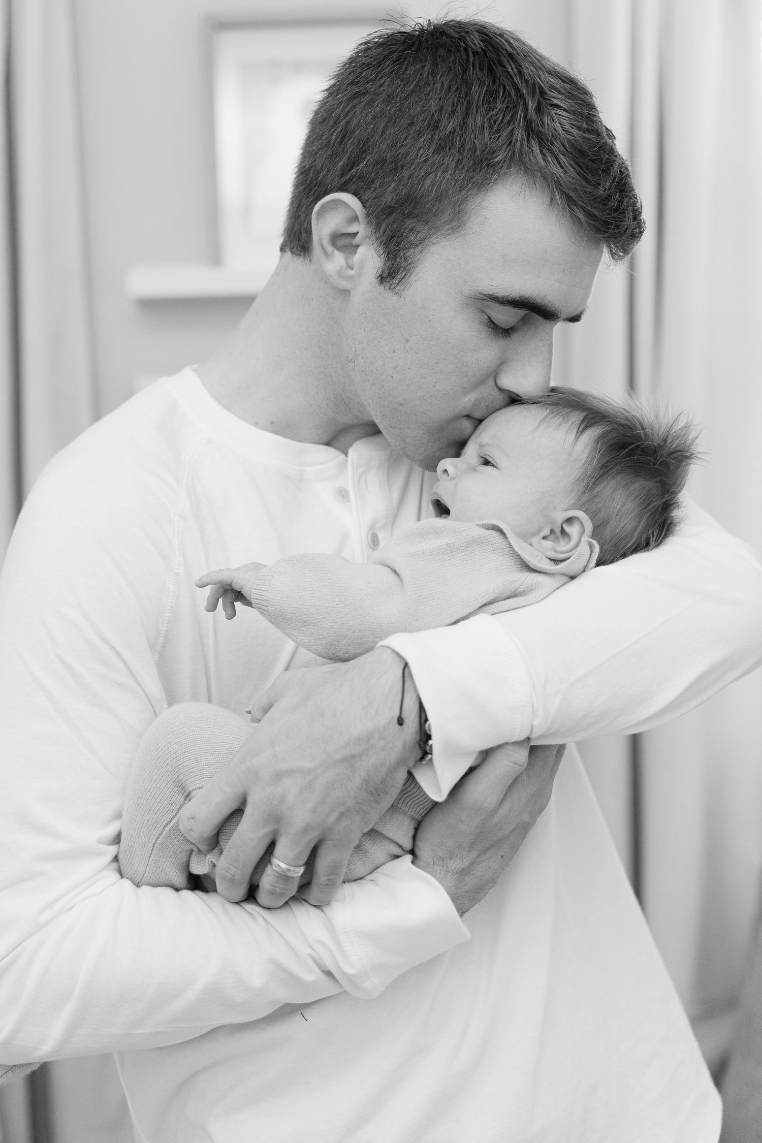 Three romantic black and white photos show a couple in white clothing sharing tender kisses.