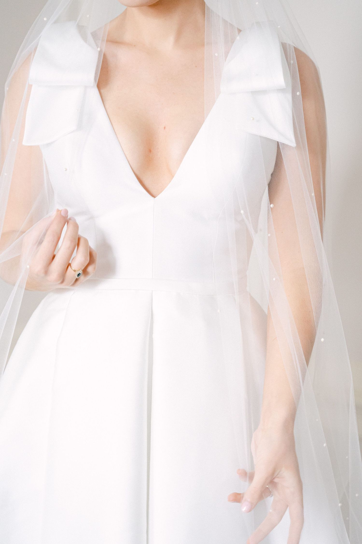 Bride in a white deep V-neck wedding gown with bow shoulders and pearl-adorned veil, elegant bridal fashion in Philadelphia, PA