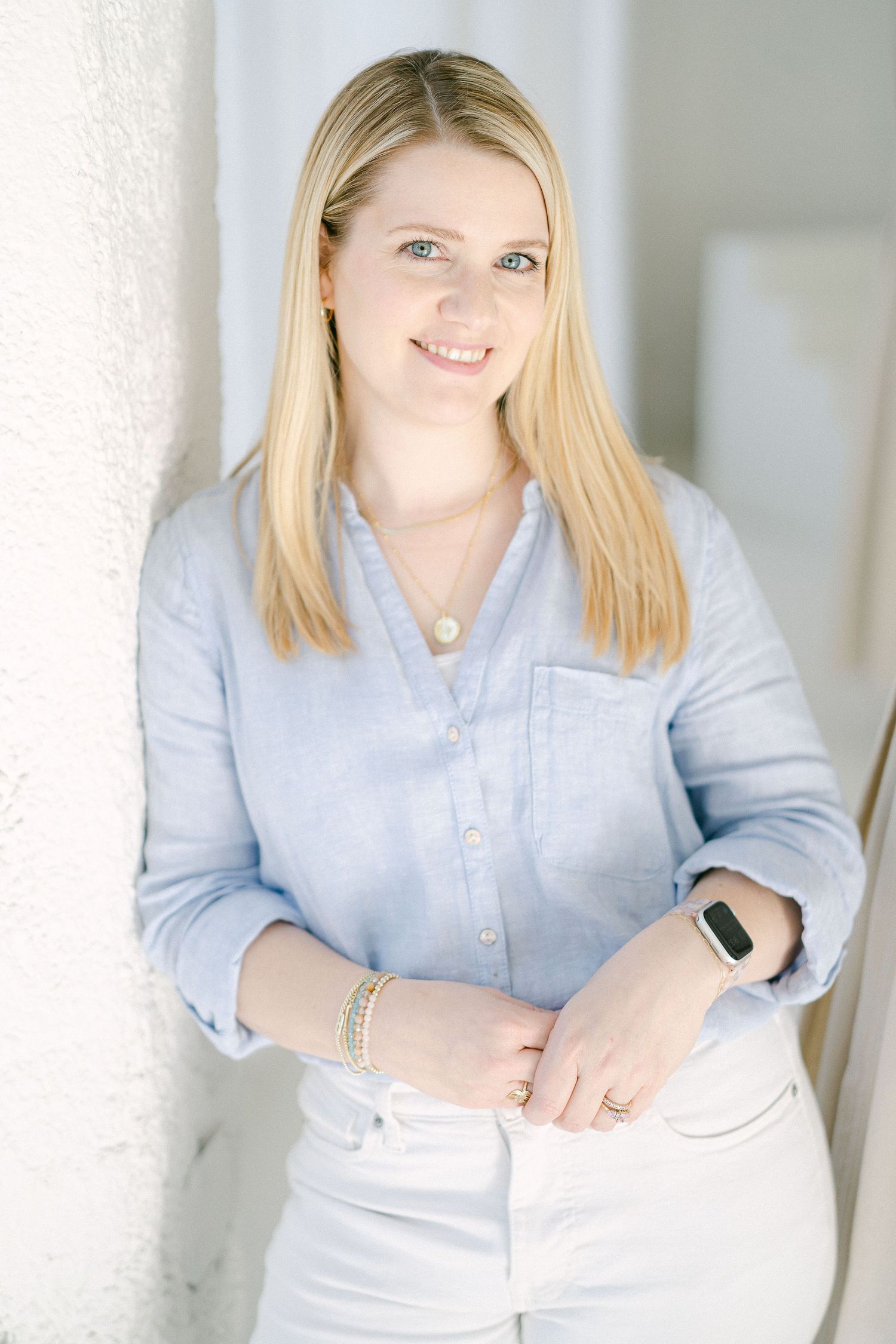 Professional headshot of someone wearing a light blue button-up shirt against a white background.