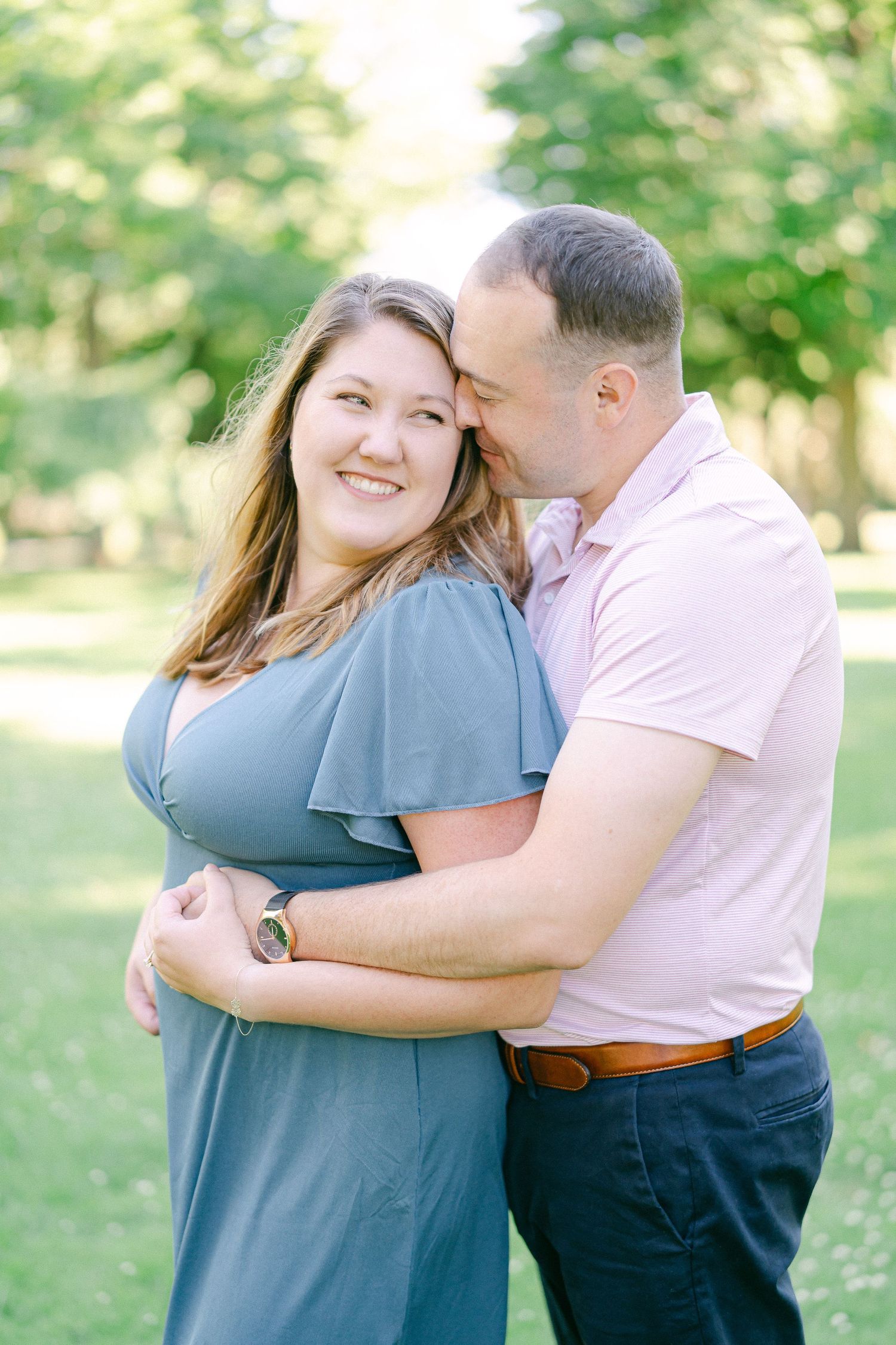A couple embraces lovingly in a series of romantic outdoor photos with natural sunlight filtering through trees.