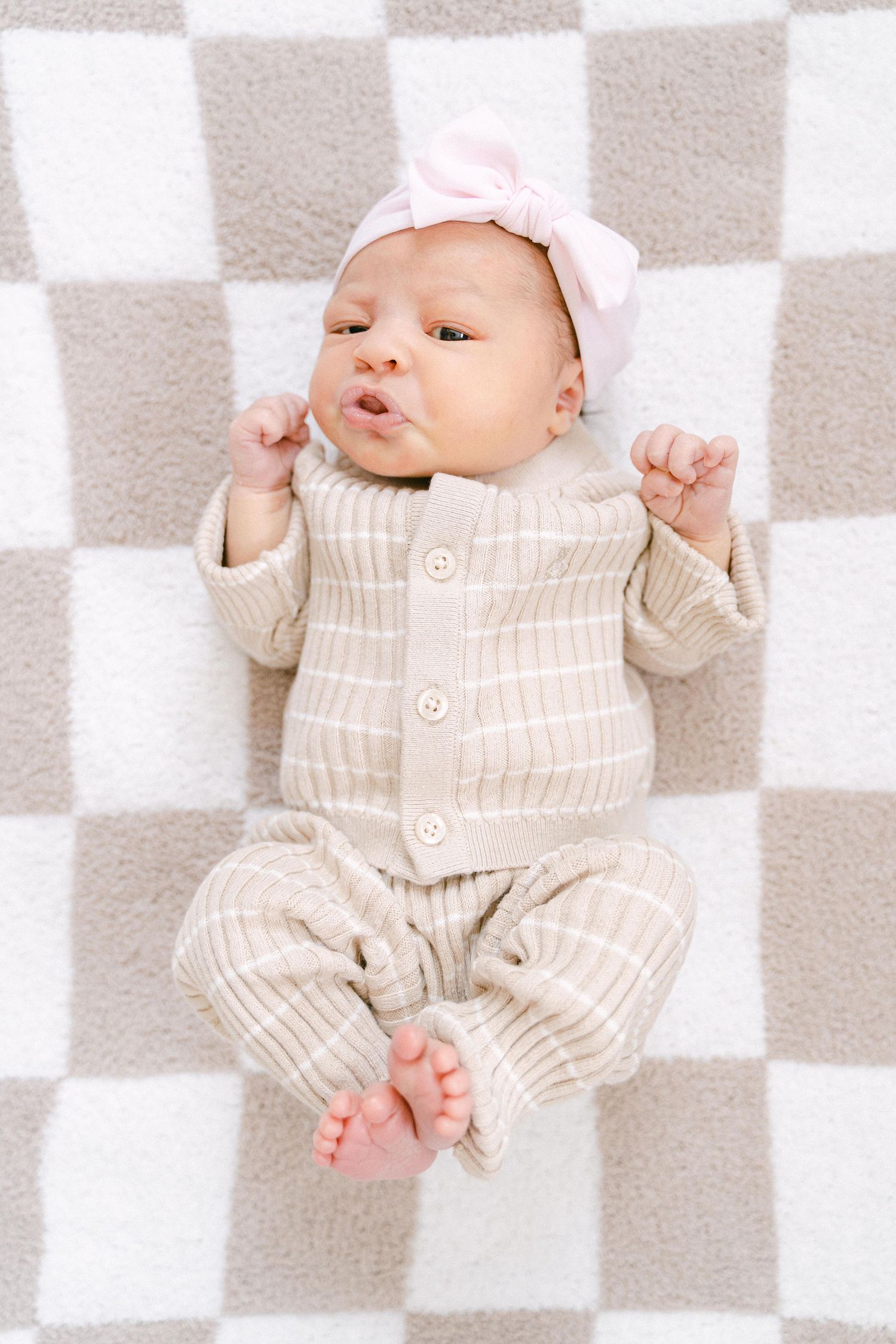 Adorable newborn baby wearing striped beige outfit lying on checkered blanket in collage-style photos.