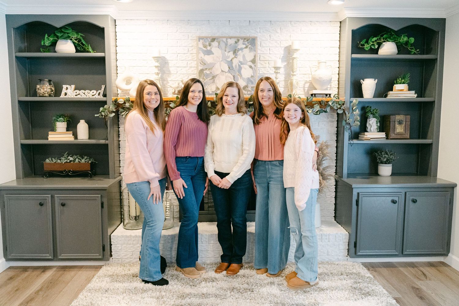 A series of gray cabinets displayed in a home interior with people standing near them showing different styling options.