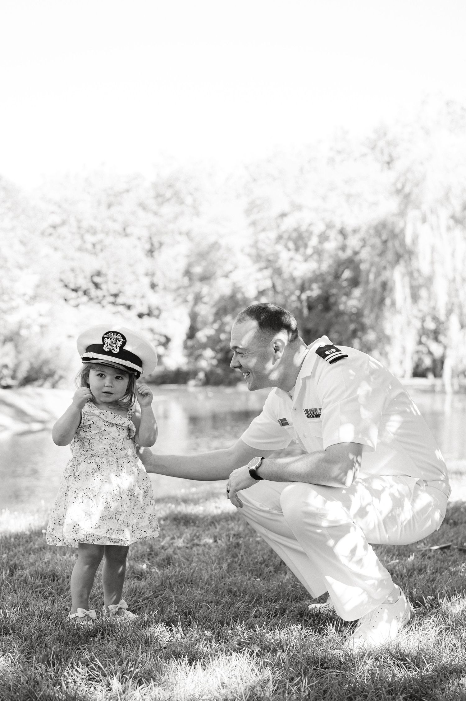 A black and white photo series shows a child in a flowy dress playing and twirling outdoors in a grassy field.
